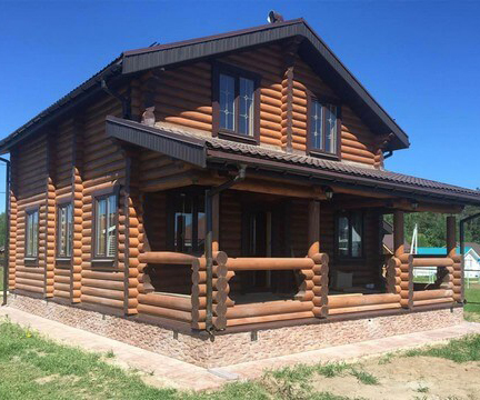 Дом из цельного бревна с цоколем, отделанным бетонной плиткой